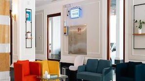 A modern lobby with a seating area featuring a glass coffee table, a red armchair, a yellow armchair, and a teal sofa. - Sunday Gateway Jeddah Formerly Beach Garden Hotel (Jeddah)