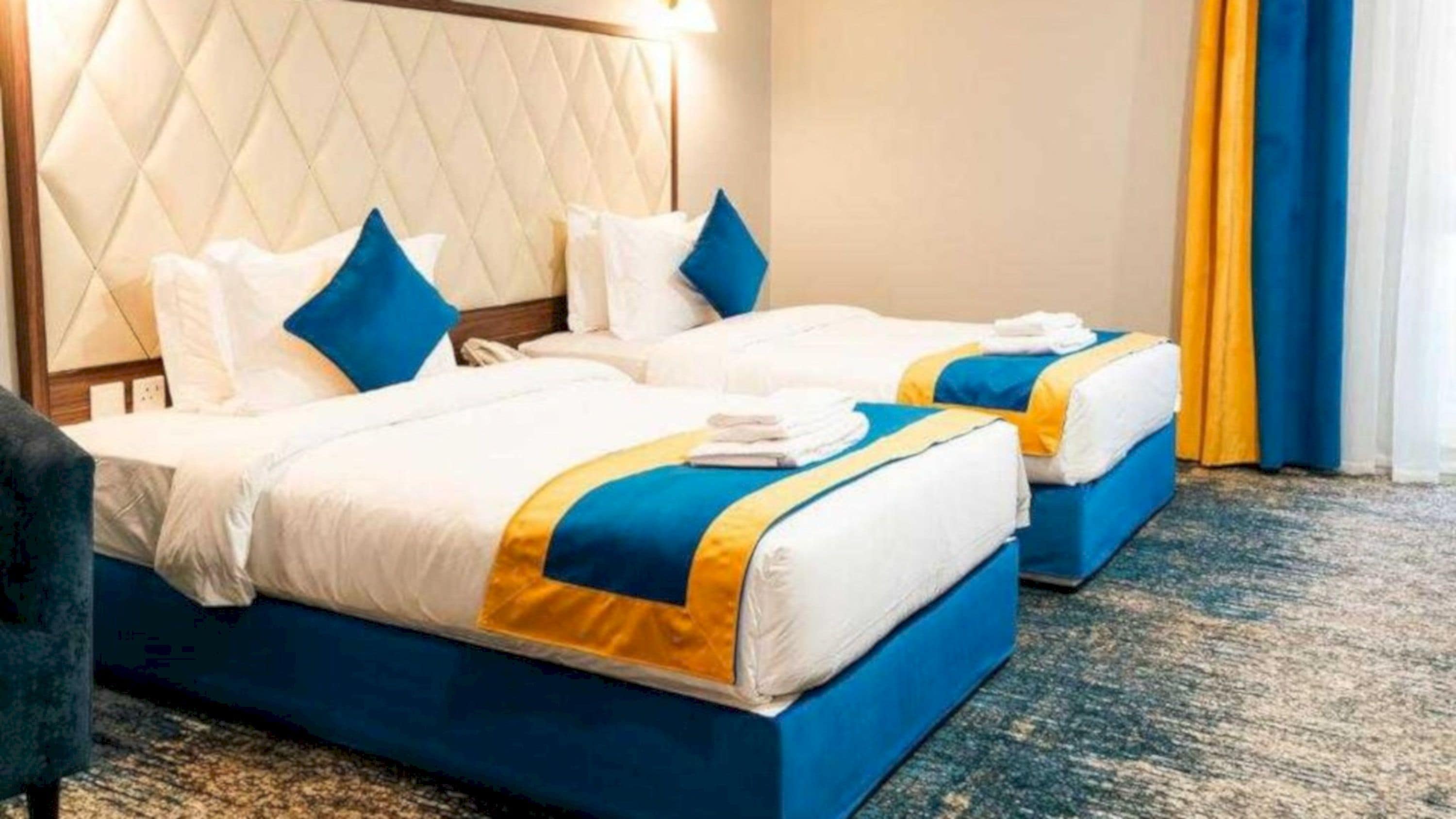 A hotel room with two beds, each with a blue and white bedspread and matching pillows.