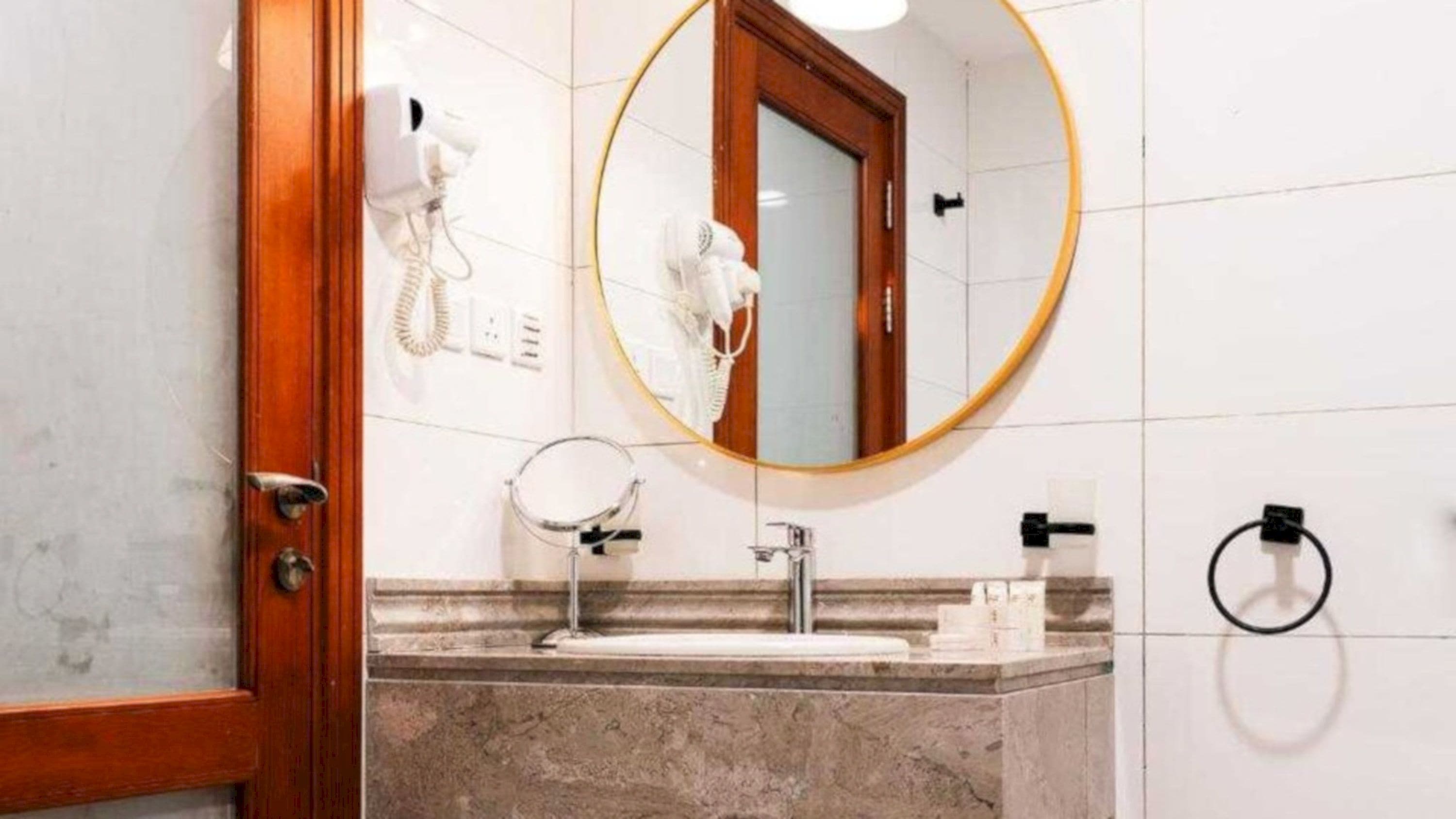 Une salle de bain avec un lavabo en marbre, un miroir, un sèche-cheveux et un porte-serviettes.