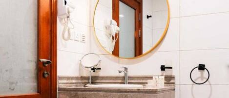 Une salle de bain avec un lavabo en marbre, un miroir, un sèche-cheveux et un porte-serviettes.
