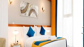 A hotel room with a bed, bedside tables, a lamp, a painting, and a window with curtains. - Sunday Gateway Jeddah Formerly Beach Garden Hotel (Jeddah)