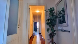 Un pasillo con suelo de baldosas, una planta en maceta y un cuadro en la pared.