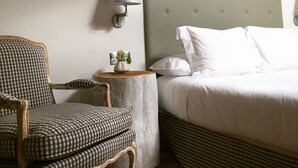 Una camera da letto con un letto, una sedia, un comodino con una lampada e una piccola pianta.