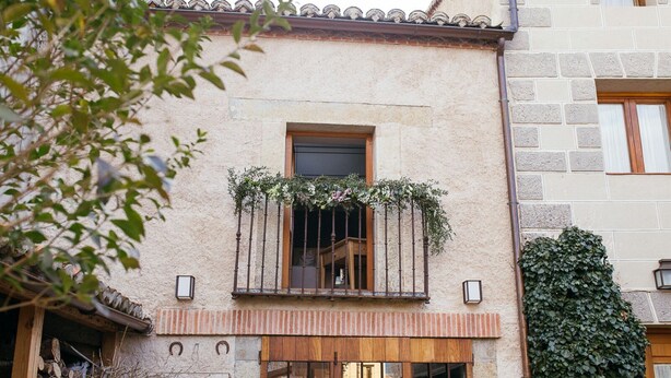 Un edificio con un balcone, una porta in legno e una finestra che offre una vista.