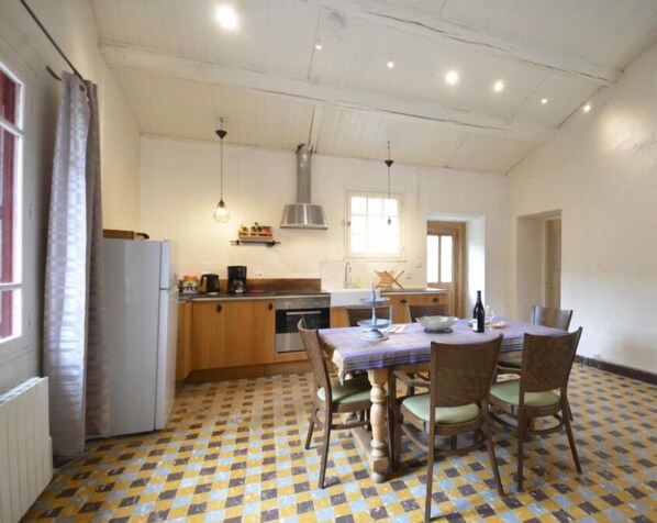 A kitchen with a dining table and chairs, a refrigerator, and a window. - Gite Syrah (Mondragon)