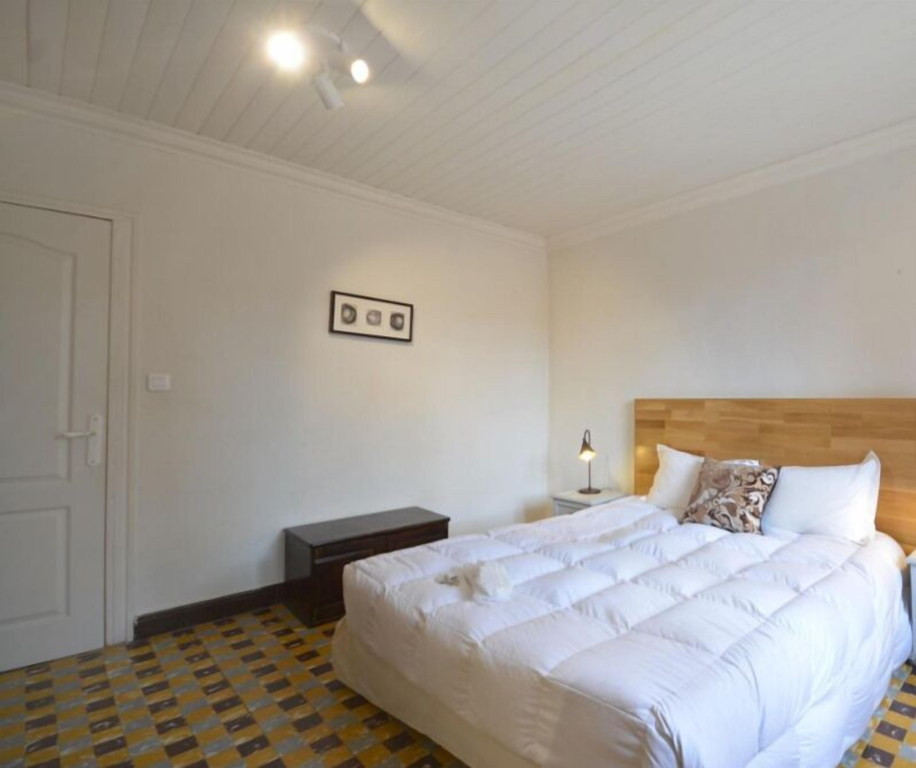 A bedroom with a bed, a nightstand, a lamp, and a ceiling fan.