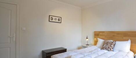 A bedroom with a bed, a nightstand, a lamp, and a ceiling fan.