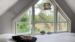A bedroom with a large window, a bed with a patterned bedspread, a black pillow, and a small decorative item on the windowsill. - 4 Star Holiday Home in Degeberga (Degeberga)
