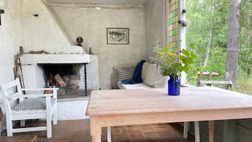 Un interior rústico con chimenea, una mesa de madera, una silla blanca y un banco.