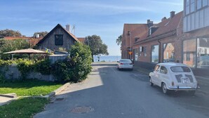 A narrow street with parked cars, a manhole cover, and a building with a red roof. - 4 Star Holiday Home in Degeberga (Degeberga)