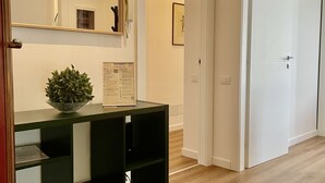 A hallway with a black console table, a framed certificate, a small plant, and a white door.