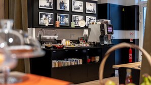 Een moderne keuken met een koffieapparaat, een fruitmand en een muur met zwart-witfoto's.