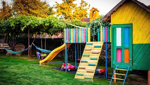 Un'area giochi colorata con uno scivolo, una parete da arrampicata e un'amaca.