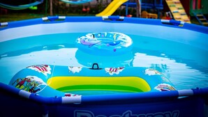 Una piscina gonfiabile blu con un pallone verde e un cerchio galleggiante.