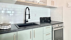 Une cuisine moderne avec un robinet noir, une cuisinière et des armoires vert clair.