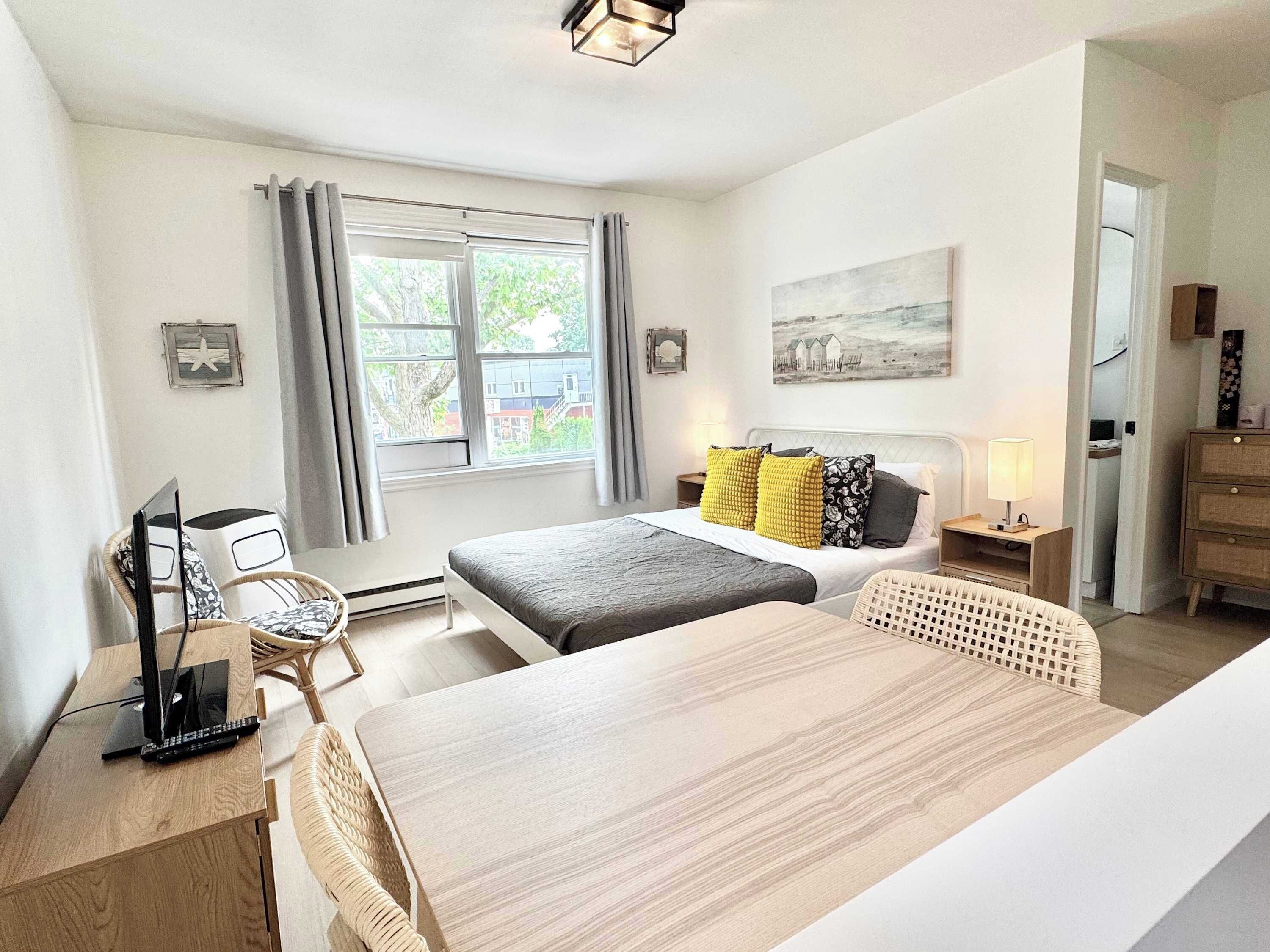 Una habitación de hotel moderna con una cama, un escritorio, una silla, una lámpara y un cuadro en la pared.
