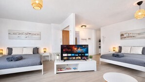 Un salon moderne avec deux canapés gris, une table basse blanche et un téléviseur à écran plat diffusant Netflix.