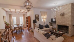 A living room with a fireplace, a sofa, a coffee table, and a dining area with a table and chairs.