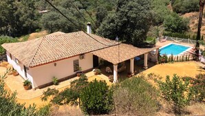A house with a tiled roof, a swimming pool, and a covered patio area.