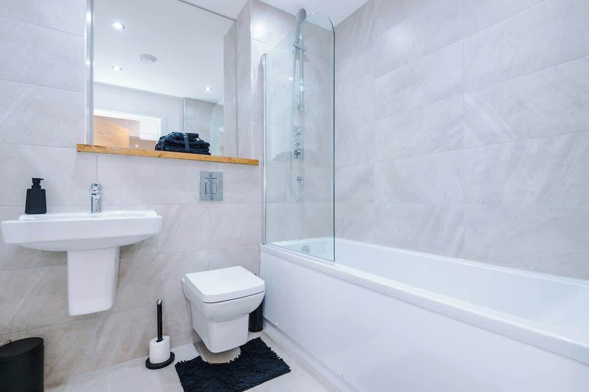 Une salle de bain moderne avec une douche à parois de verre, un lavabo blanc et des toilettes.