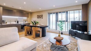 A modern living room with a sofa, a coffee table, and a TV. - Luxury City Apt with Balcony & Parking (Leeds)