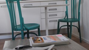 Une cuisine moderne avec des armoires blanches, une hotte de couleur grise et deux chaises turquoise.