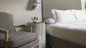 Une chambre à coucher comprenant un lit, une chaise, une table de chevet avec une lampe et un luminaire fixé au mur.