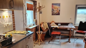 A kitchen with wooden cabinets, a tiled backsplash, and a dining area with a table and chairs.