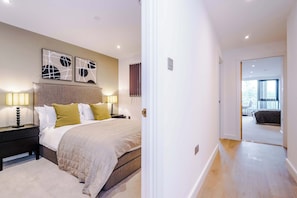 A bedroom with a bed, bedside lamps, a headboard, and abstract wall art.