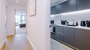 Ett modernt kök med grå skåp, en inbyggd ugn och en bänkskiva med en kaffebryggare och andra köksapparater.