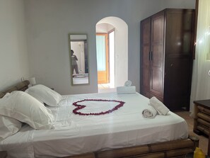 A hotel room with a bed, a wardrobe, a mirror, and a view of the hallway.
