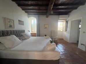 A bedroom with a large bed, a chair, and a window.