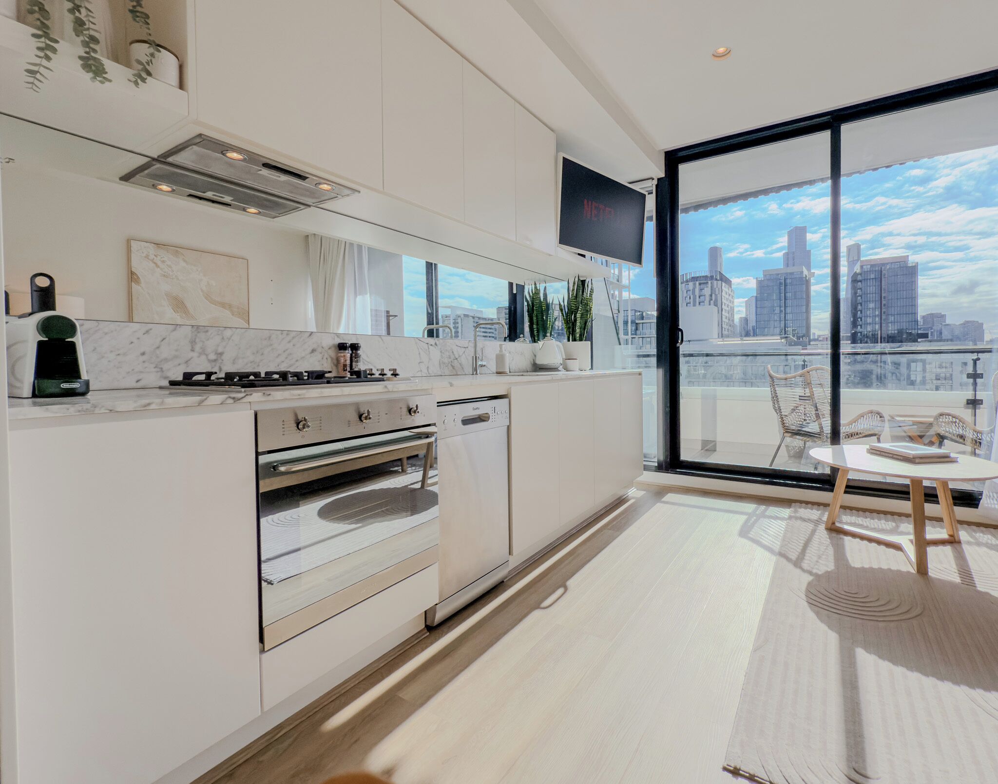 Eine moderne Küche mit Backofen, ein Essbereich mit Tisch und Stühlen und ein großes Fenster mit Blick auf die Stadt.