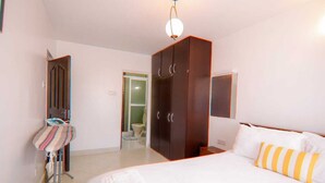 Een slaapkamer met een bed, een kledingkast, een spiegel en een deur naar een badkamer.