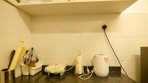 Een keukentrap met een koffiezetapparaat, een waterkoker en een houder voor keukengerei.