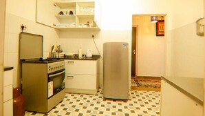 Een compacte keuken met een fornuis, koelkast en bovenkastjes.