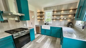 Une cuisine moderne avec des meubles de couleur turquoise, une cuisinière en acier inoxydable et un lave-vaisselle encastré.