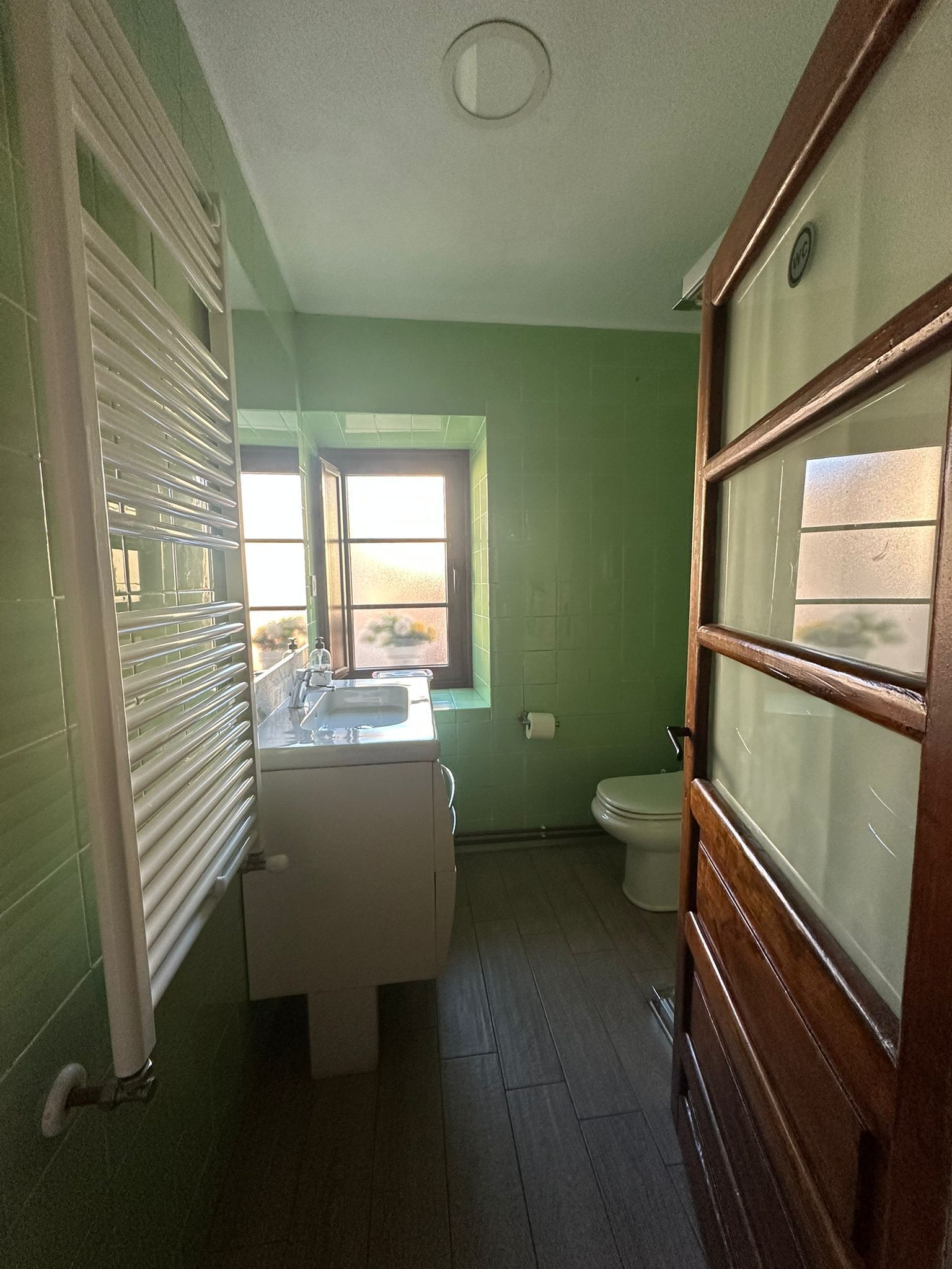 A bathroom with a toilet, a sink, and a window.