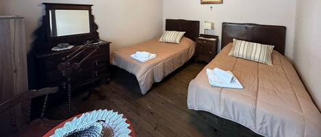 Un dormitorio con dos camas, muebles de madera, una araña y un cuadro en la pared.