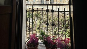 Un balcón con plantas en macetas y vistas a un edificio de piedra con tejado de tejas rojas.