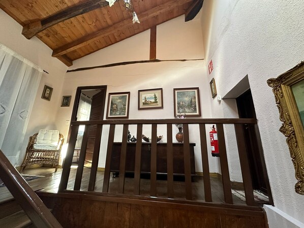A wooden staircase with a railing leading to a room with a high ceiling and wooden beams.