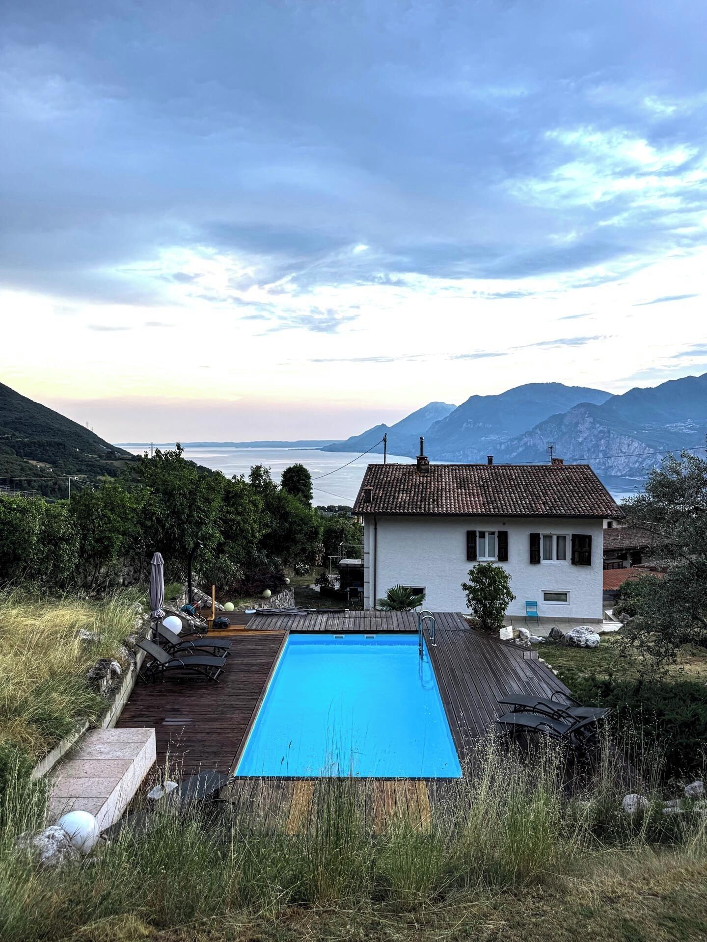 A house with a swimming pool, surrounded by a wooden deck and a garden.