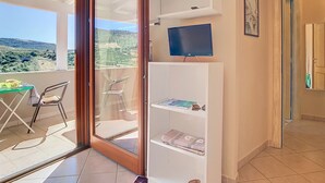 A balcony with a table and chairs, a TV on a shelf, and a view of the countryside. - Villa Surrounded by Nature Bbq Privacy Sea Relax (Castelsardo)