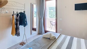 A bedroom with a bed, a TV, a window, and a balcony with a chair. - Villa Surrounded by Nature Bbq Privacy Sea Relax (Castelsardo)