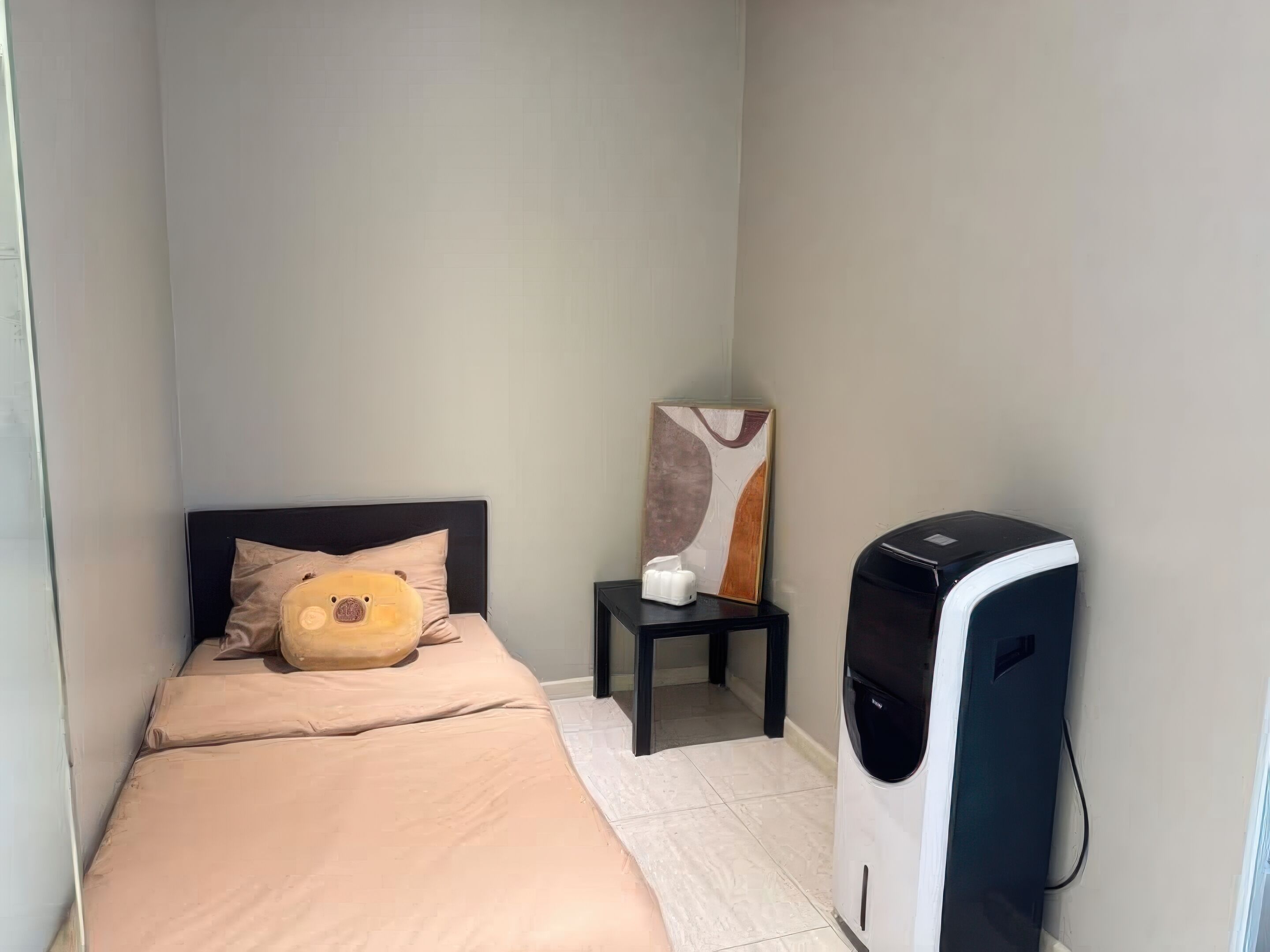 A small bedroom with a bed, a bedside table with a lamp, and a heater.