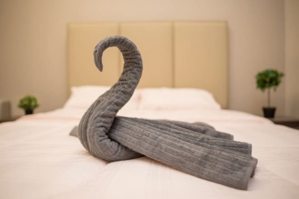 Una cama bien hecha con una toalla con forma de cisne.