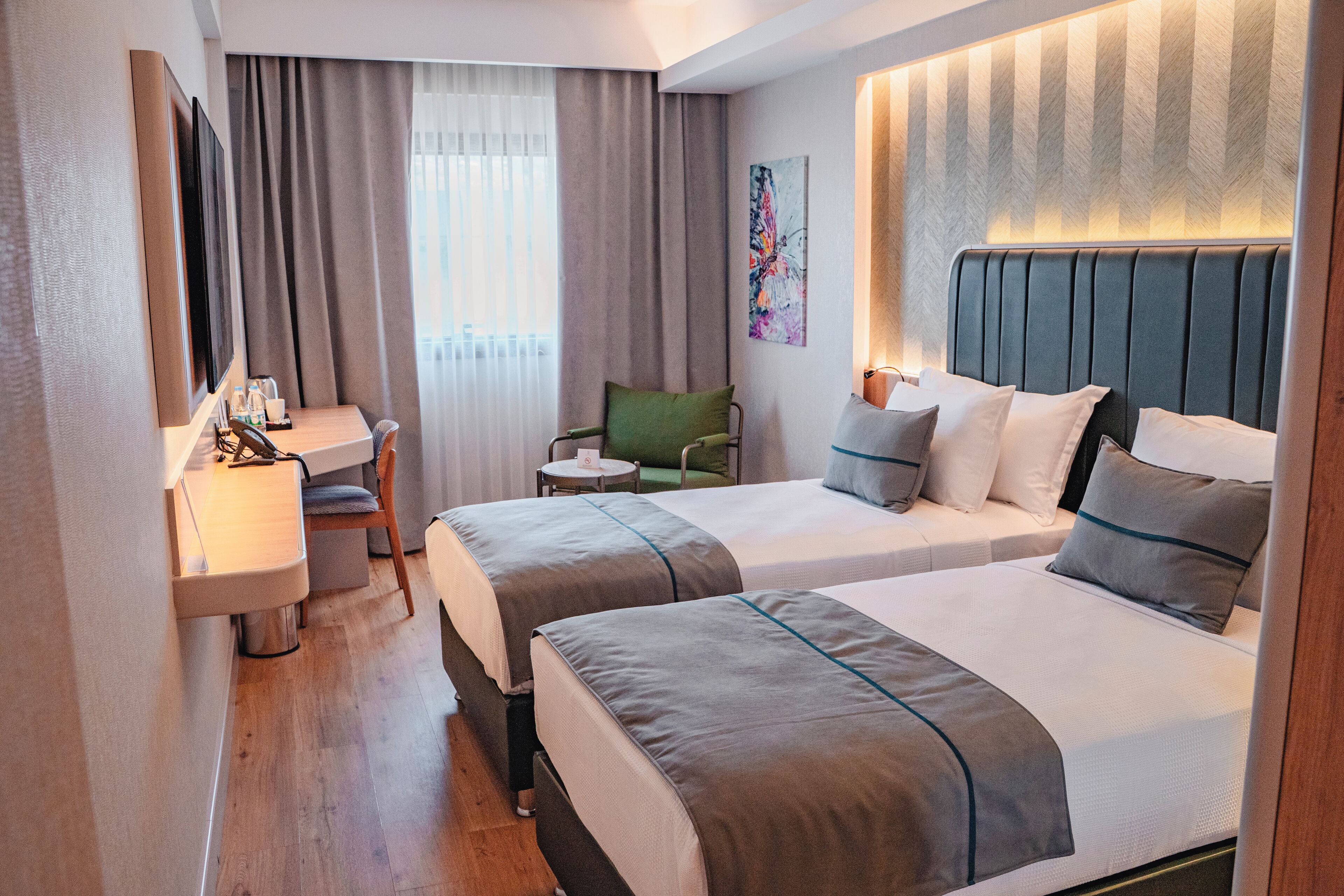 Een hotelkamer met twee bedden, een bureau, een stoel en een klein tafeltje.