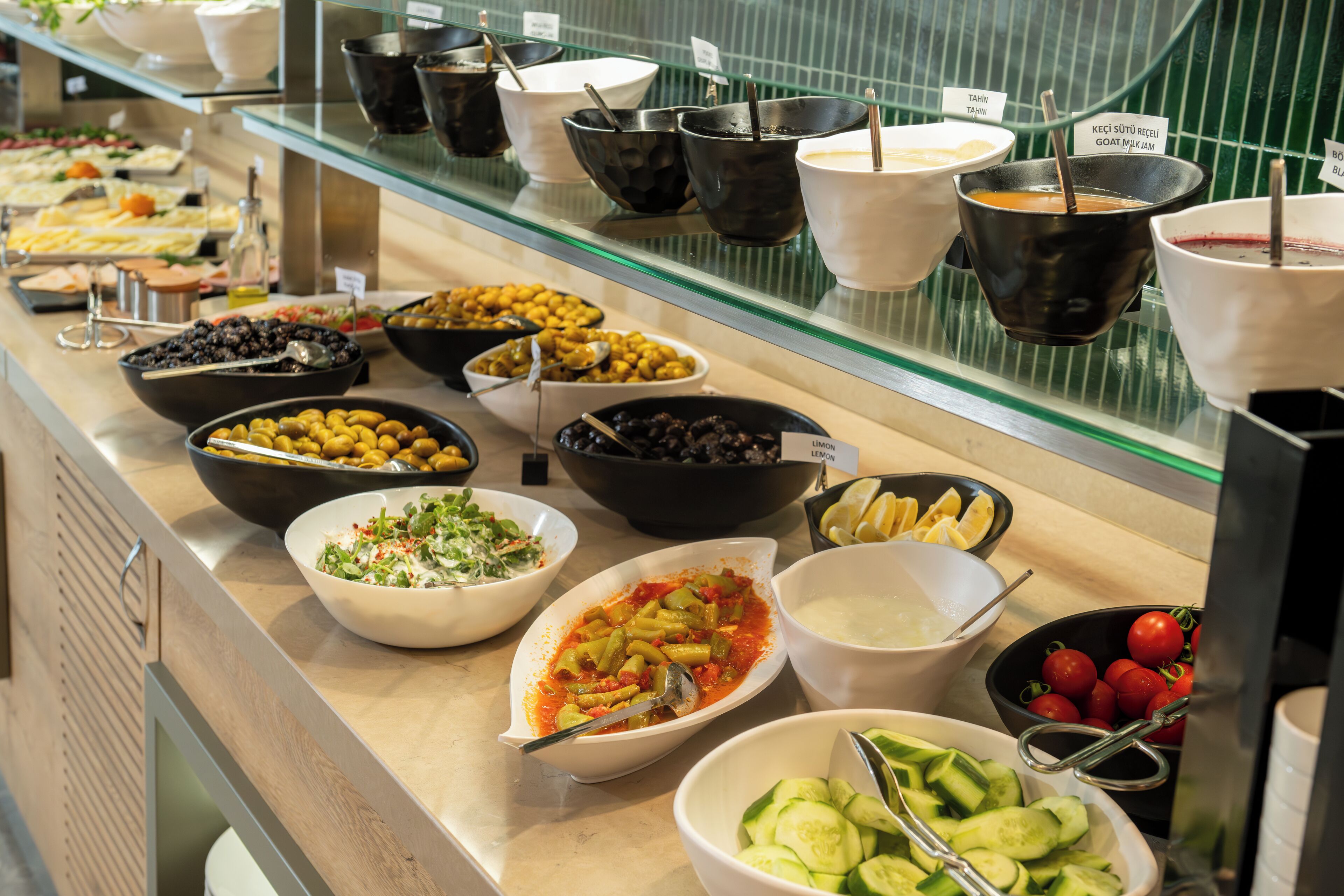 A buffet with various food options including salads, pasta, and fruits.