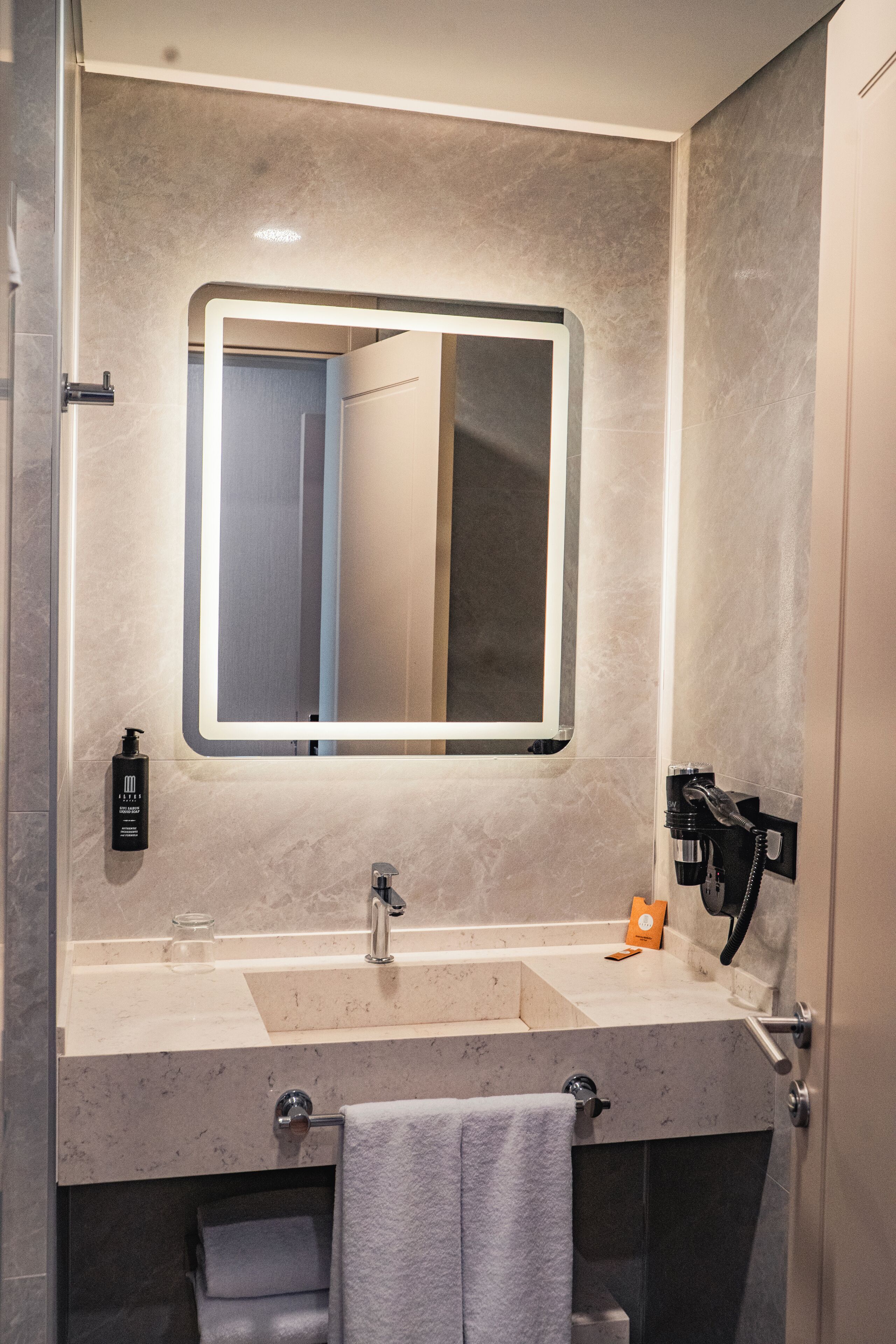 Une salle de bain moderne avec un grand miroir, un lavabo et un porte-serviettes.