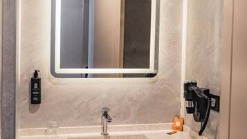 Une salle de bain moderne avec un grand miroir, un lavabo et un porte-serviettes.